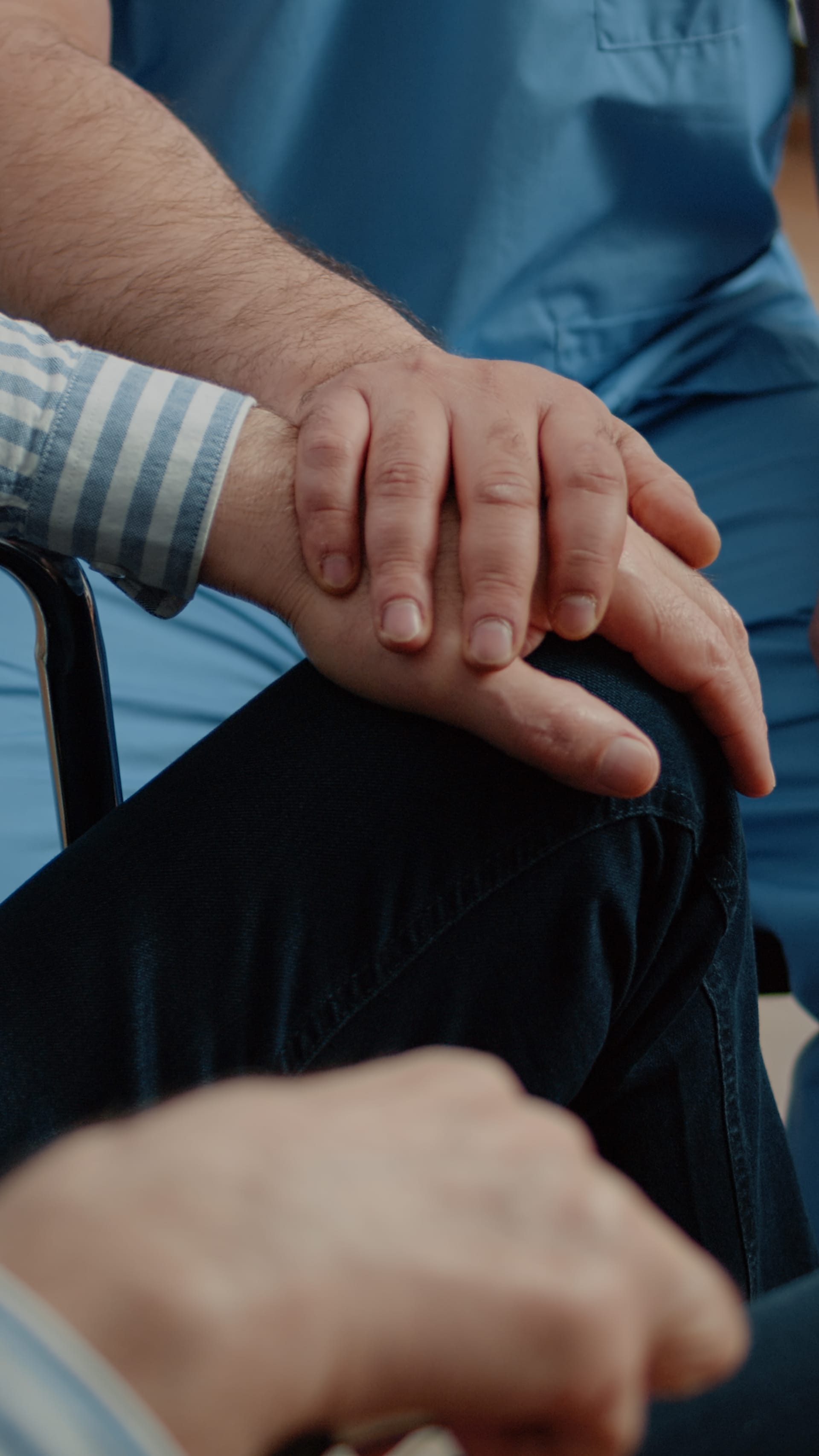 A nurse's hand resting on a patient's hand, offering comfort and support