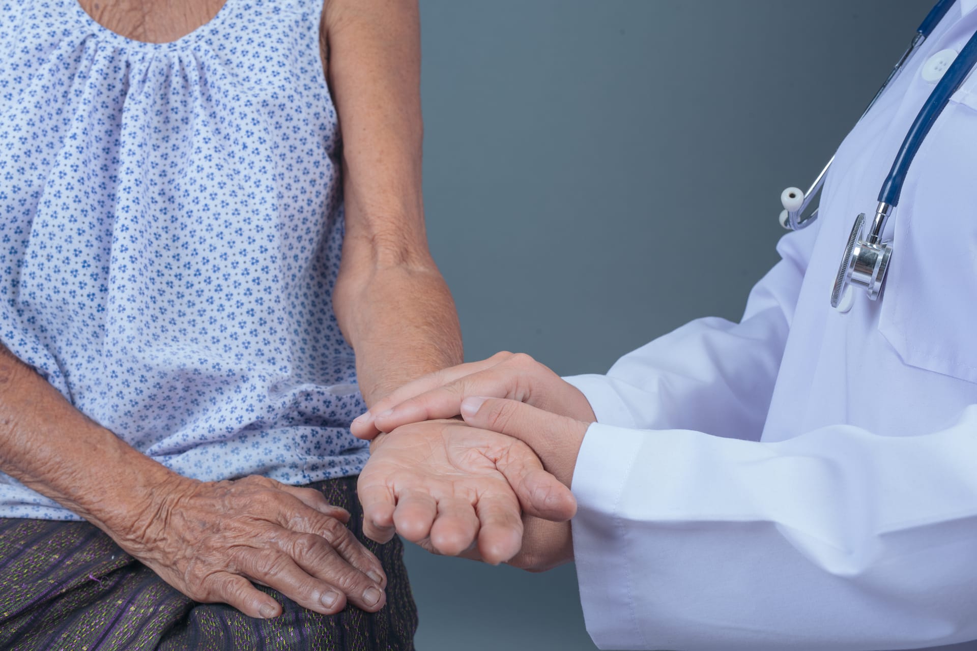 A physician checking a patient's pulse, a caring hand held reassuringly